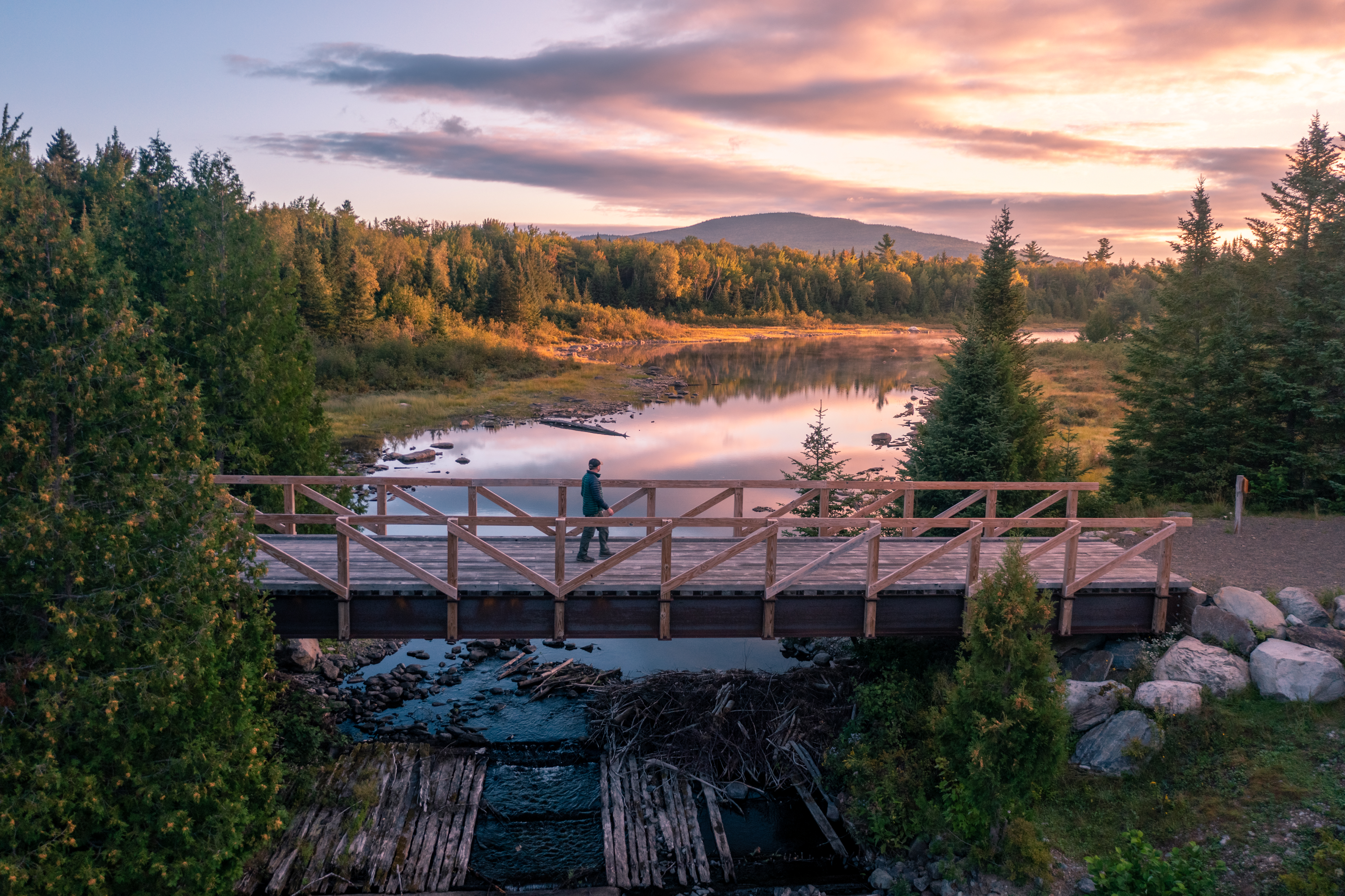 man walking across bridge in Maine Woods