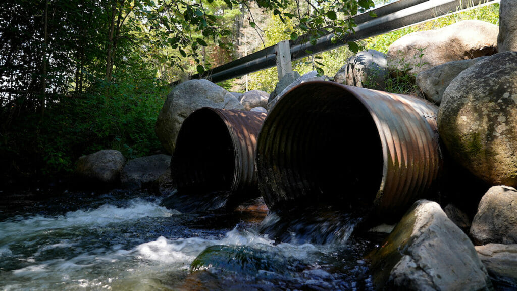 Two rusting culverts with rushing water